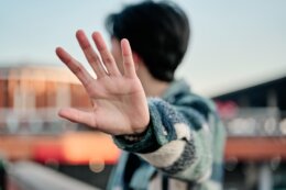 Young,Asian,Man,Covering,His,Face,In,A,Stop,Sign.
